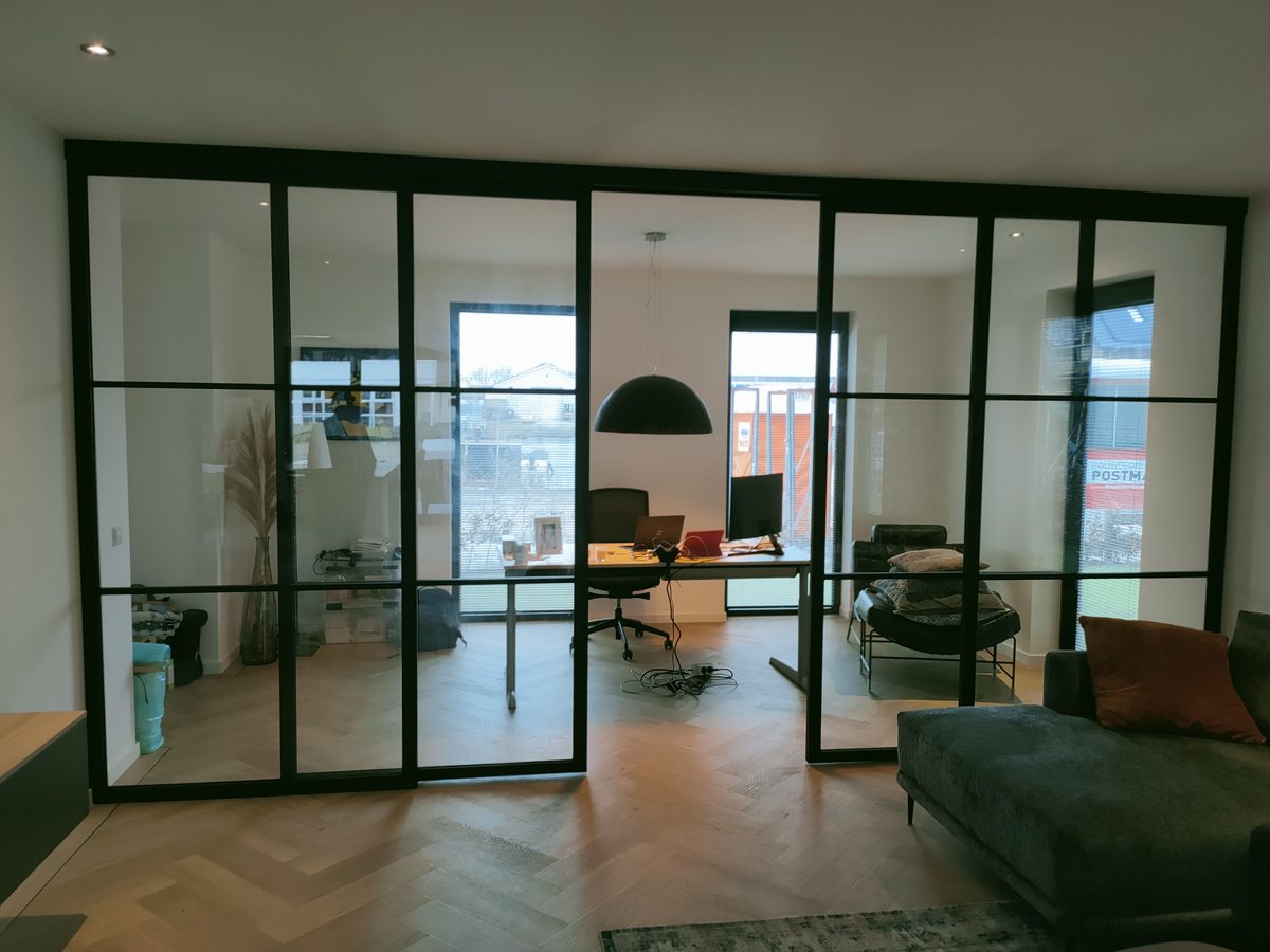 Glazen wand met deuren en zwart kader, op maat gemaakt voor een woonkamer