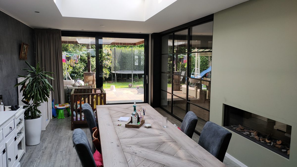 Glazen schuifdeuren met zwart kader op maat, met zicht op de tuin