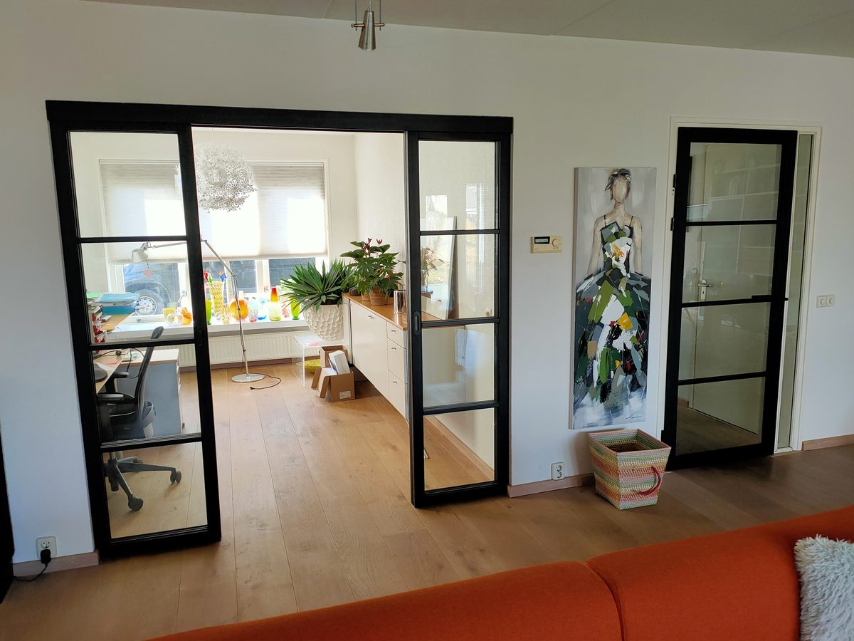 Glazen schuifdeuren met zwart kader op maat tussen woonkamer en werkkamer