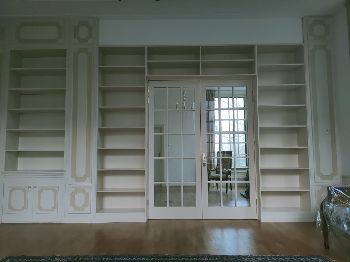 Witte boekenkast op maat in een klassiek interieur met paneelwanden
