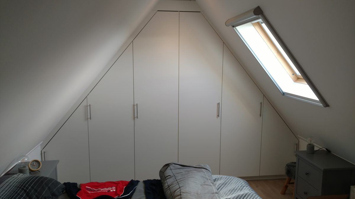 Witte inbouwkast op maat onder een schuin dak