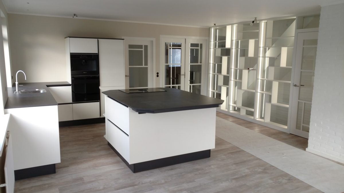 Witte keuken met kookeiland en een open vakkenkast als roomdivider