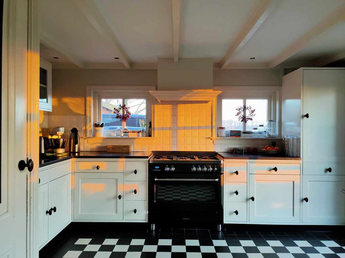 Klassieke witte keuken op maat met paneeldeurtjes en zwart-wit geblokte vloer