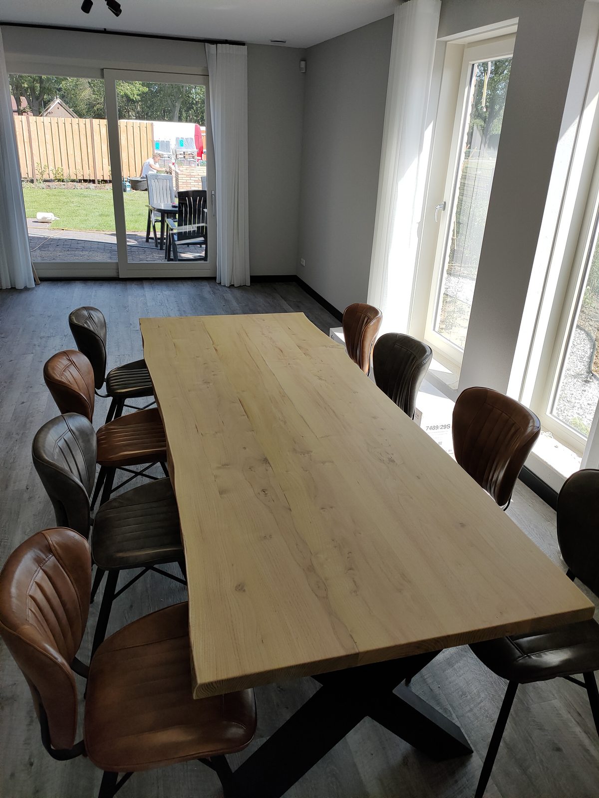 Massief houten eettafel op maat met zwarte kruispoot en leren stoelen