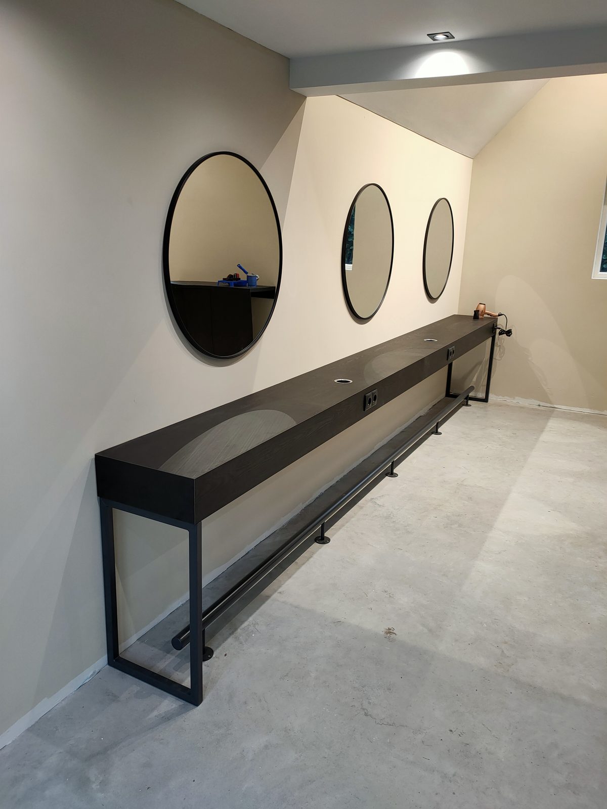 Lange zwarte wandtafel op maat met ronde spiegels in een bedrijfsruimte